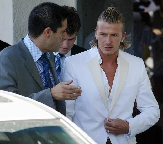 young David Beckham in a white suit walking to a car