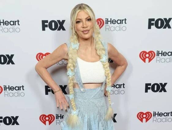 Person with long braids on red carpet wearing a textured gown and crop top at an iHeart Radio event, posing for photos
