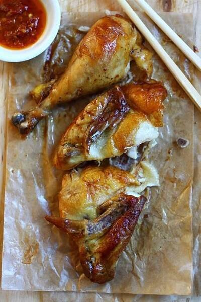 two pieces of chicken sitting on top of wax paper next to chopsticks and sauce