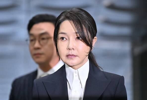 South Korea First Lady Kim Keon Hee in formal black suit bowing in public apology, flanked by officials, at a press conference in Seoul.