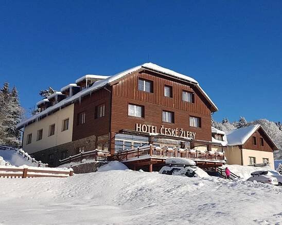 a building with a sign on it in the snow at Hotel České Žleby in Stožec