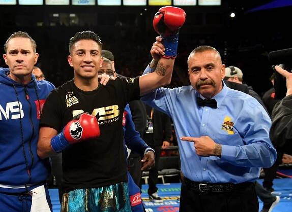 a boxer wearing a shirt that says ns stands next to a referee