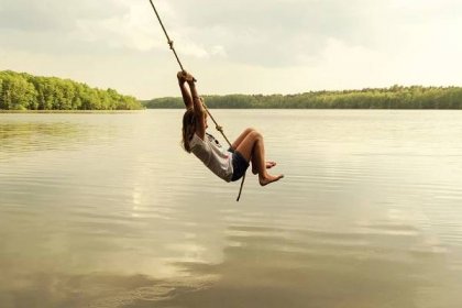A child on a rope swing above the water