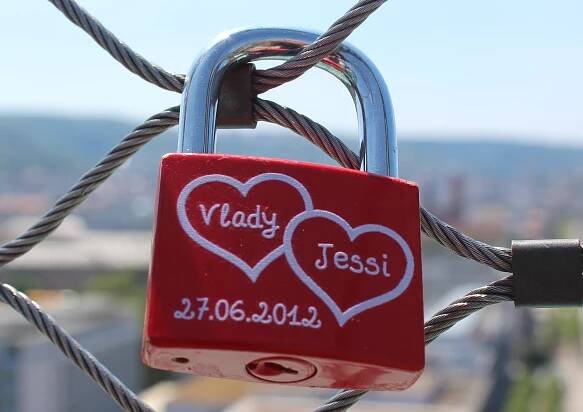 Červený zámek s namalovanými jmény páru v srdíčkách a datem zamčení