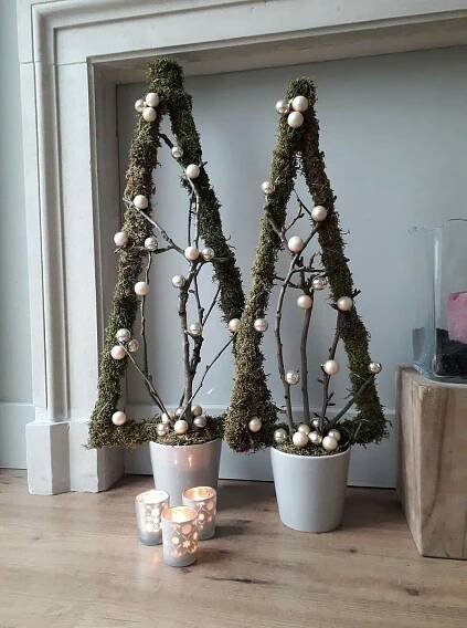 two potted plants with white balls on them in front of a fireplace mantel