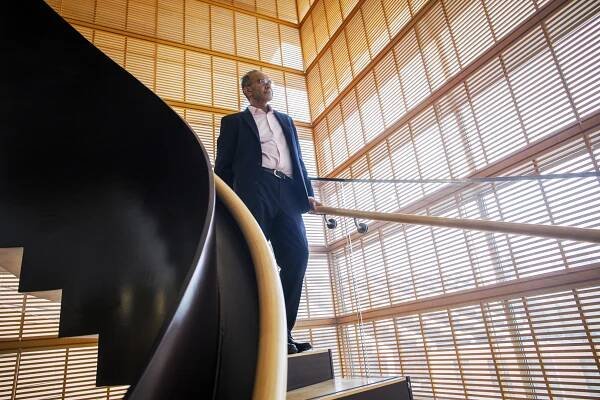 Tarun Khanna stands on a staircase in front of windows