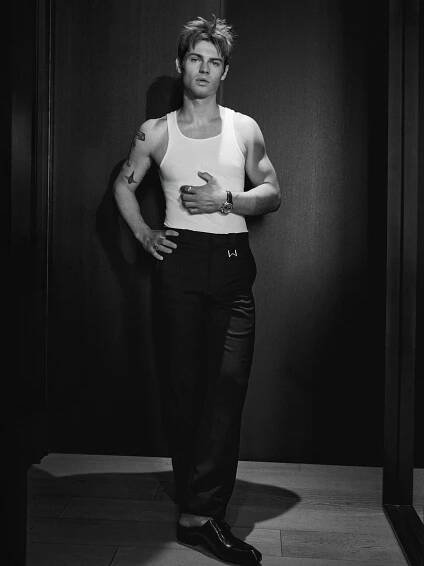 My Life With the Walter Boys actor Noah LaLonde poses wearing a white tank top with black pants and shoes.