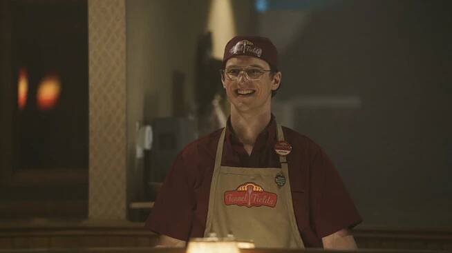Freddie Stroma as Adrian/Vigilante on Peacemaker season 1 in his Fennel Fields uniform looking excited