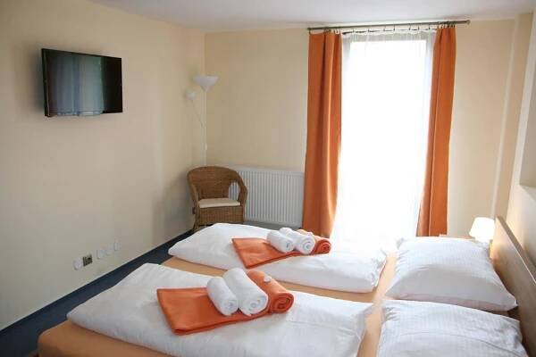 two beds in a hotel room with towels on them at Hotel Praha Potštejn in Potštejn