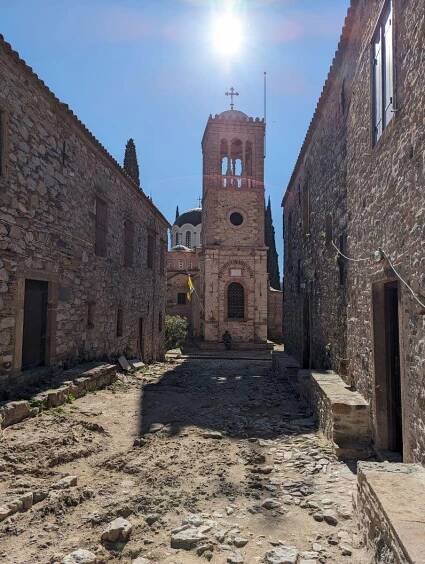 Ancient Nea Moni Monastery on Chios island, showcasing Byzantine architecture with a bell tower against a clear sky, a serene historical site for travelers exploring beyond Chios town.