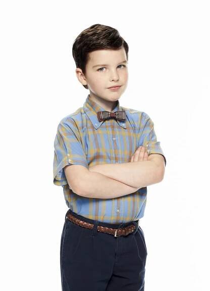 a young boy wearing a bow tie standing with his arms crossed