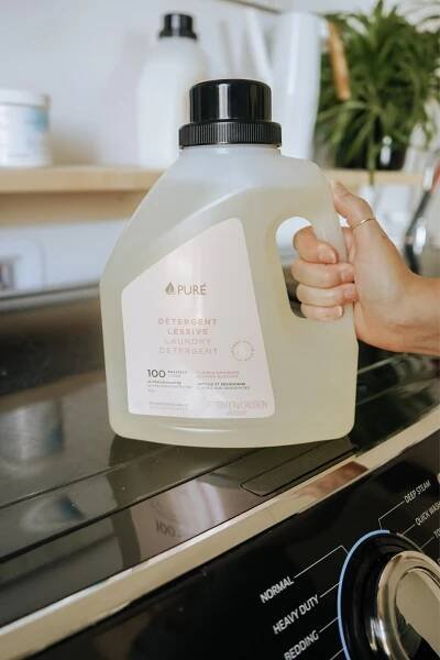 A woman holding a bottle of PURE biodegradable laundry detergent. 