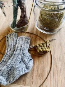 knit baby socks laying on wood with jars 