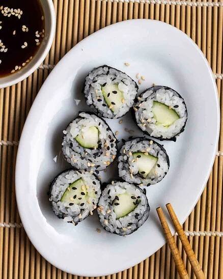 6 kappa maki on a oval plate with chopsticks and soy sauce beside.