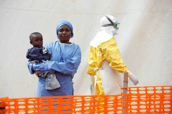 Mwamini Kahindo, an Ebola survivor working as a caregiver to babies who are confirmed Ebola cases, holds an infant outside the red zone at the Ebola treatment centre in Butembo, Democratic Republic of Congo.