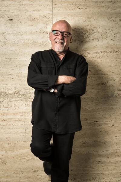 Smějící se Paulo Coelho opřený o zeď