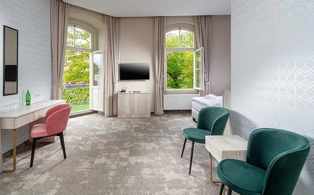 a living room with chairs and a table and a tv at Esplanade, dependance hotelu Monti Spa in Františkovy Lázně