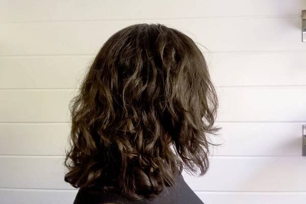 A persons hair to the side after styling with the DevaCurl SuperCream Coconut Curl Styler