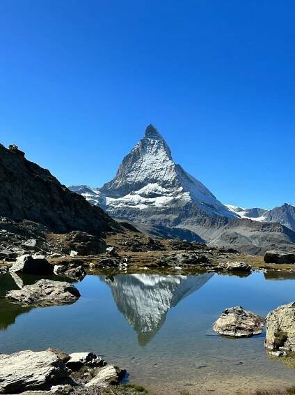 Free Beautiful reflection of Matterhorn in a serene alpine lake under a clear blue sky in Zermatt, Switzerland. Stock Photo