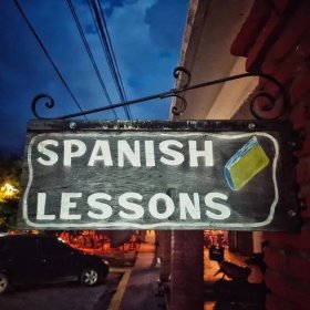 A wooden sign advertising Spanish lessons