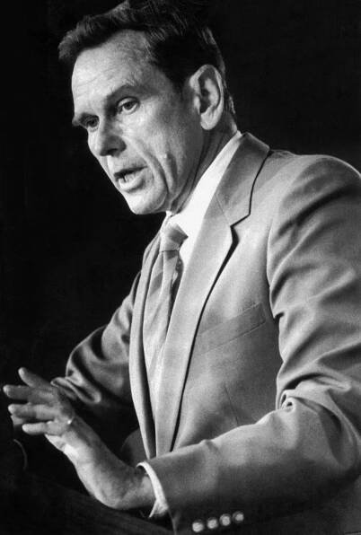 A black-and-white photograph of Richard Murphy, wearing a gray suit, white shirt and striped tie.