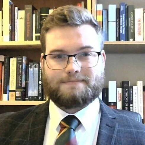 Jake Scott is a man with a beard wearing a suit