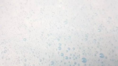 Bílá pěna s bublinkami praskání v modré vodě detailní up — Stock záběr