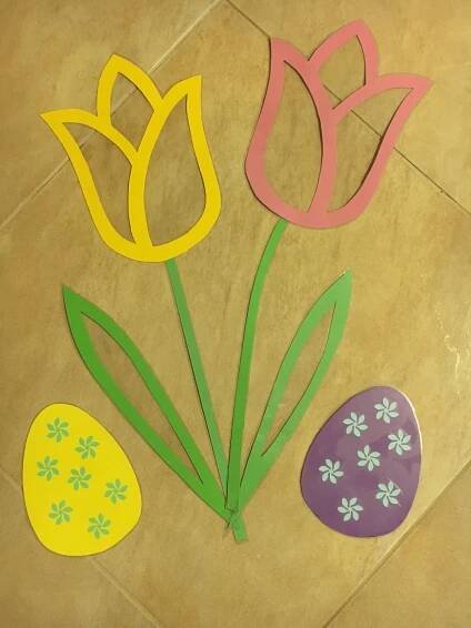 paper flowers and easter eggs on the floor in front of a tiled flooring area