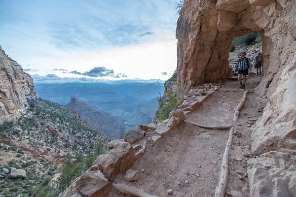 People hiking down a steep mountain side path.
