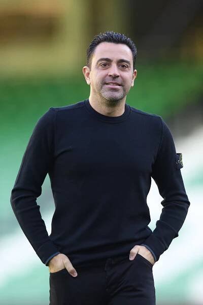 a man wearing a black stone island sweater stands with his hands in his pockets