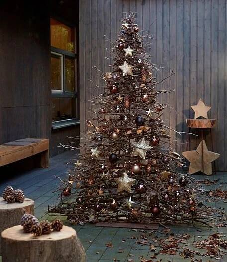 a small christmas tree is on the ground in front of a wooden wall and star decorations
