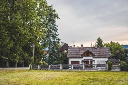 a white house with a fence in a field at Penzion u lázní in Velké Losiny