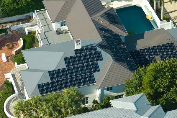 Luftaufnahme eines teuren amerikanischen Hausdachs mit blauen Photovoltaik-Sonnenkollektoren zur Produktion sauberer ökologischer elektrischer Energie. Investitionen in erneuerbaren Strom zur Altersvorsorge. — Stockbild