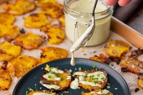 drizzling lemon chive dressing over duck fat smashed potatoes.