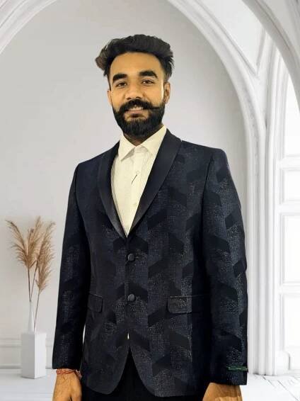 The scene you describe seems to depict a well-composed setting, potentially for a portrait or a formal occasion. The mans attire suggests a sense of elegance and style, with the dark patterned suit jacket providing contrast against the white shirt. The well-lit room likely accentuates both the mans features and his clothing, while also highlighting other elements in the room. The white arched window can serve as an architectural focal point that adds depth to the composition, and the decorative dried grass in a vase may introduce an organic touch that complements the overall aesthetic of the scene.