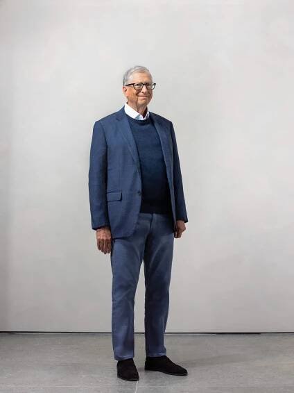 Bill Gates smiling and standing against a light backdrop.