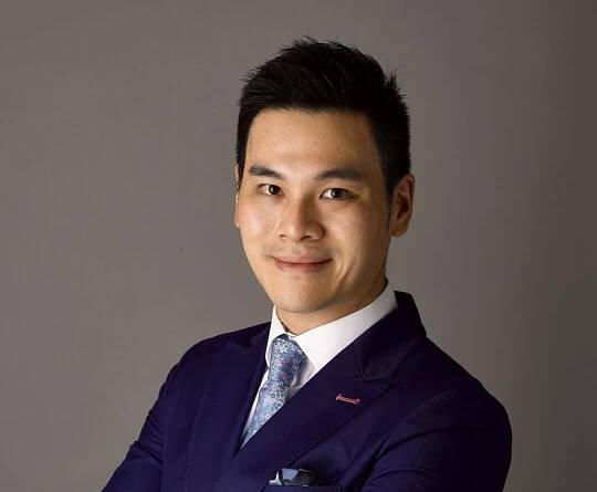 Portrait of an Asian young man wearing a blue suit. Kwok is a leading auctioneer and holds a key role in Sotheby's expansion in tehe Asian Region