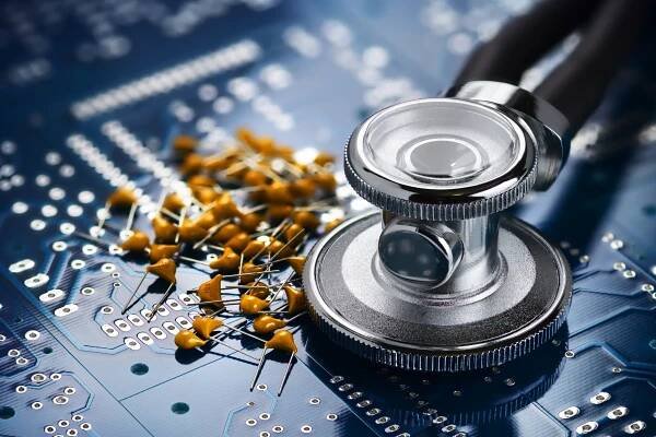 A stethoscope and yellow capacitors placed on a blue PCB, symbolizing reliable PCB assemblies for medical devices and diagnostic tools.