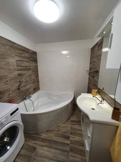 a bathroom with a tub and a sink and a washing machine at Apartmány Nová duha Vavřinec in Vavřinec
