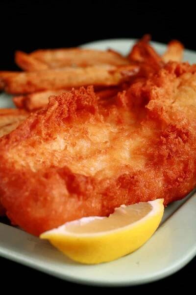 A plate of gluten-free fish and chips, with a wedge of lemon.
