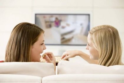Dvě ženy v obývacím pokoji televizi jíst čokoládu s — Stock obrázek