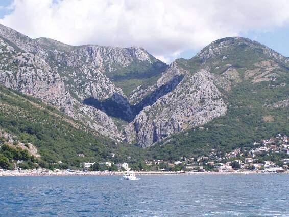 Sutomore. Dole pláž a nad ní majestátní hory.