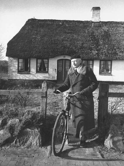 Der alte Heinz Reinefarth mit seinem Fahrrad vor einem mit Reet gedeckten Haus