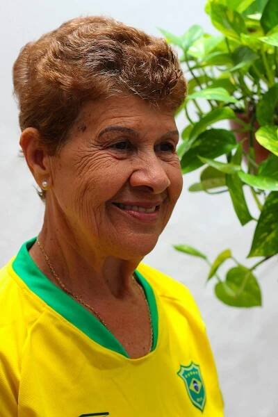 Free Portrait of a smiling elderly woman wearing a Brazil soccer jersey, set in São Paulo. Stock Photo