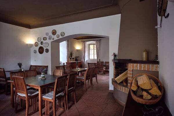 a restaurant with tables and chairs and a fireplace at Penzion Černická obora in Bechyně
