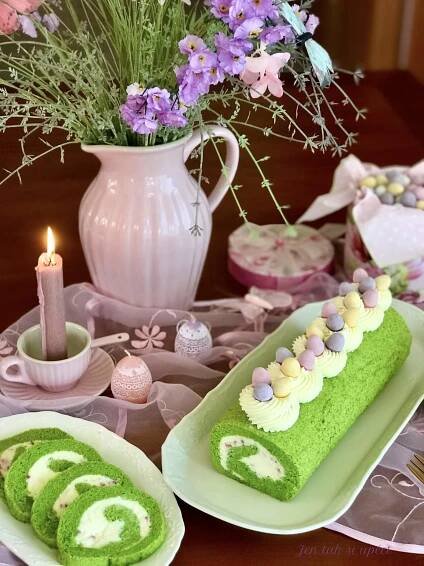 a table topped with plates filled with green cake next to a vase full of flowers