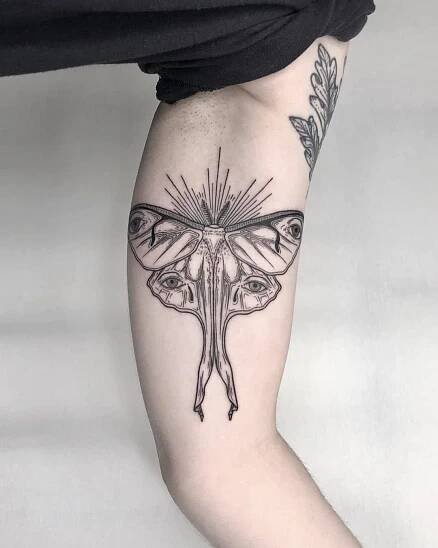 a woman's leg with a moth tattoo on it and an arrow in the middle