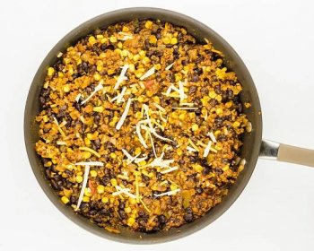 A skillet is full of beans and other ingredients to make vegan taco casserole.