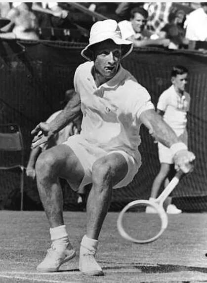 A black-and-white photograph of a man playing tennis.