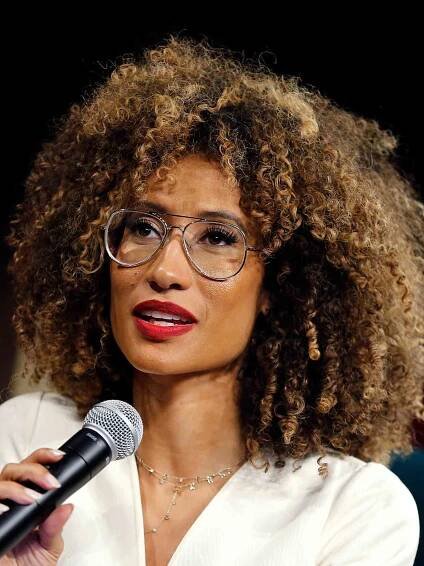 Elaine Welteroth with hair in natural curls wearing red lipstick and metal aviator eyeglasses
